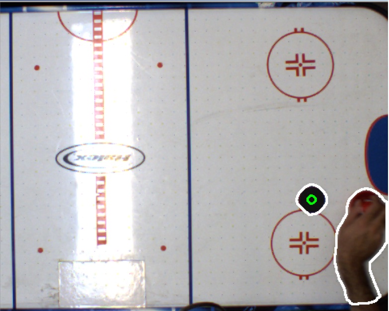 Overhead view of an air hockey table with a computer-vision overlay tracking the puck.