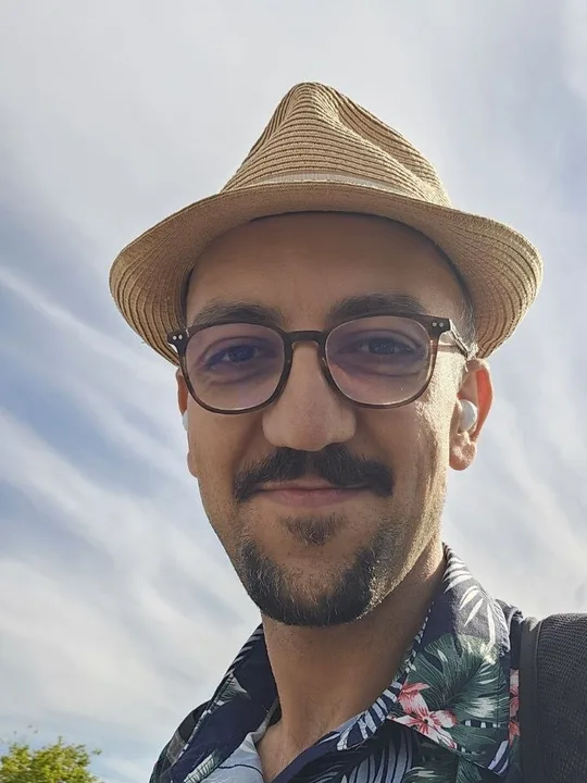 Hesam Alizadeh wearing a straw hat and glasses outdoors.